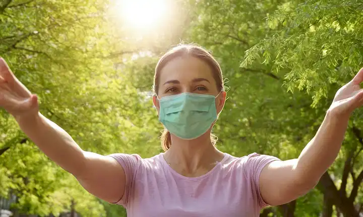 Árboles verdes, paisaje urbano, mujer sonriente, sol brillante, manos extendidas, símbolo de cáncer, máscara de contaminación del aire, renovación urbana