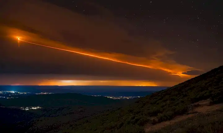 Reentrada de satélite, luz de estiércol, sendero brillante, cielo nocturno, paisaje peninsular, perno artificial, brillo naranja, nubes oscuras, horizonte iluminado
