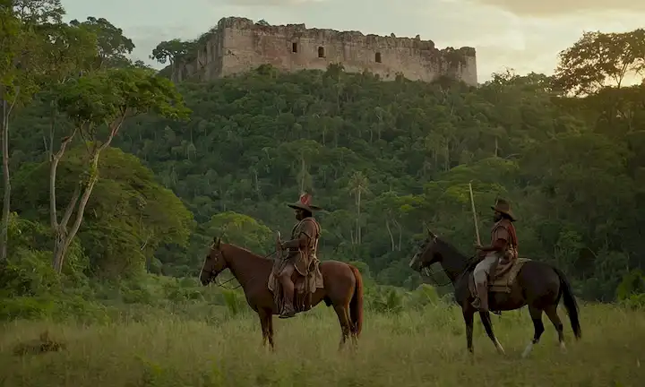 conquistadores españoles del siglo XVI montando caballos junto a indígenas americanos a caballo, en una exuberante selva o bosque, con antiguas ruinas o artefactos visibles en el fondo, y una atmósfera de atardecer o crepúsculo