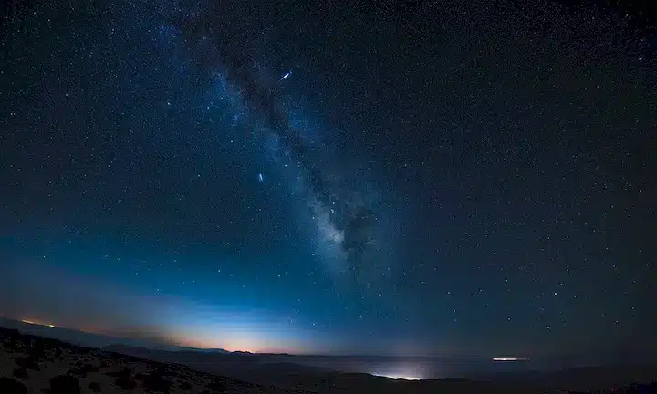 distante cúmulo de galaxias, vasta extensión del espacio, luz azul débil, tendriles wispy de gas, Earendels resplandor, nubes cósmicas, fondo estrellado, oscuridad misteriosa, belleza celestial, lejanía profunda, maravilla astronómica