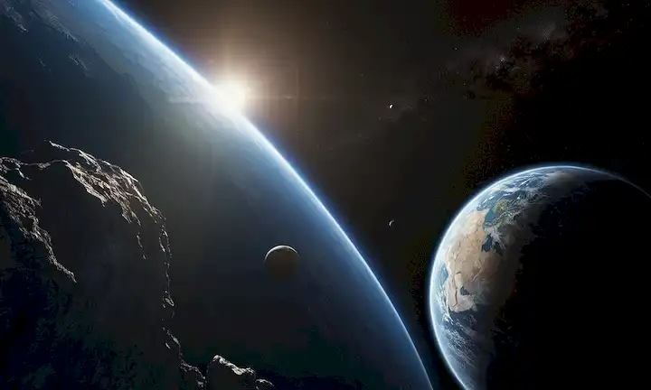Un satélite orbita la Tierra, un asteroide grande se cierne en el fondo, la luz del sol refleja su superficie, una sombra sutil cae a través de una parte de la superficie de los planetas